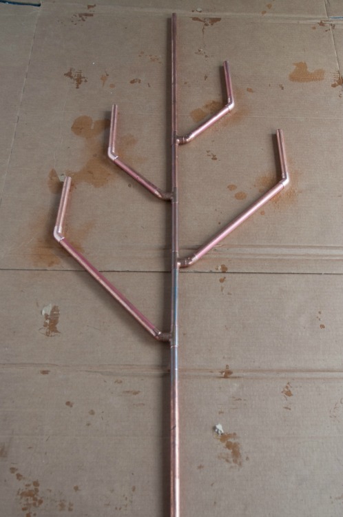 Completed copper body for glass bottle tree sculpture on cardboard
