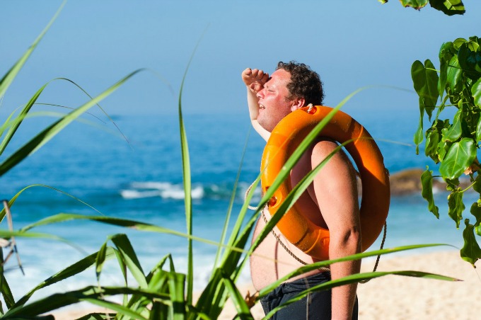 Average man at the beach with a life preserver