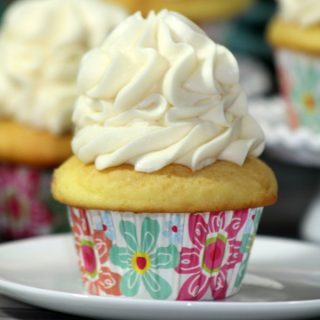 one single cupcake sitting on a white plate, in a pink and teal flower cupcake liner