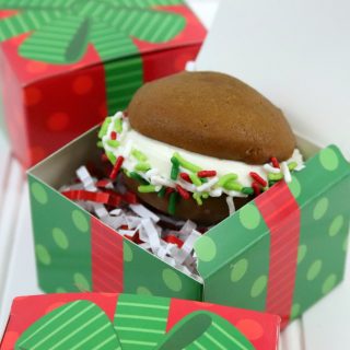 a gingerbread whoopie pie with holiday sprinkles sitting in a green and red holiday gift box