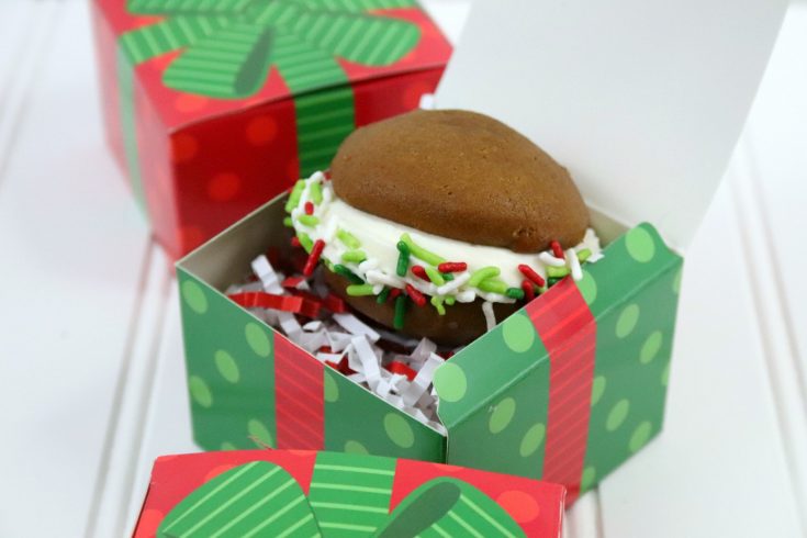 a gingerbread whoopie pie with holiday sprinkles sitting in a green and red holiday gift box