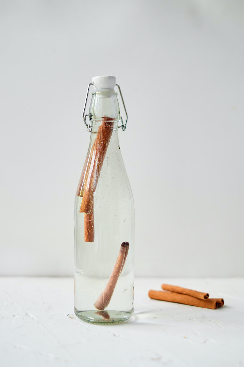 a tall glass jar filled with vodka and cinnamon sticks to make homemade cinnamon extract 