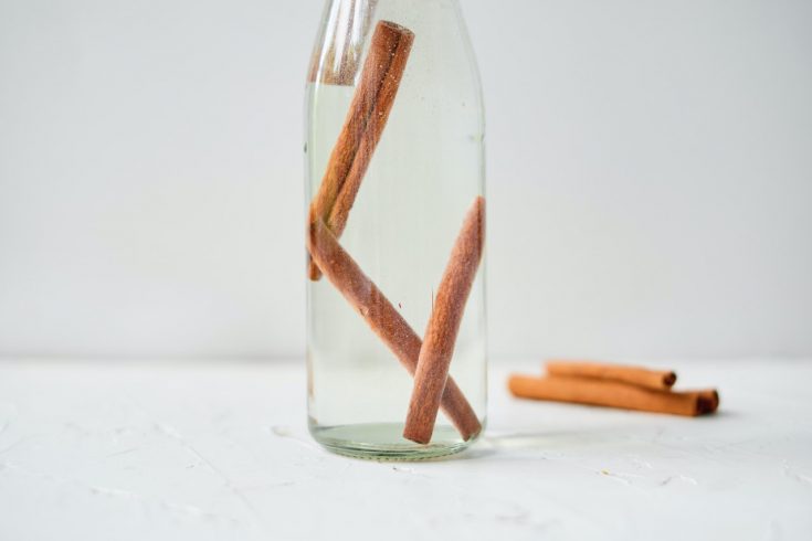 a clear bottle of vodka with cinnamon sticks