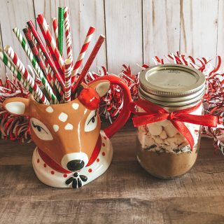a mason jar filled with hot chocolate mix sitting next to reindeer mug filled with colorful paper straws