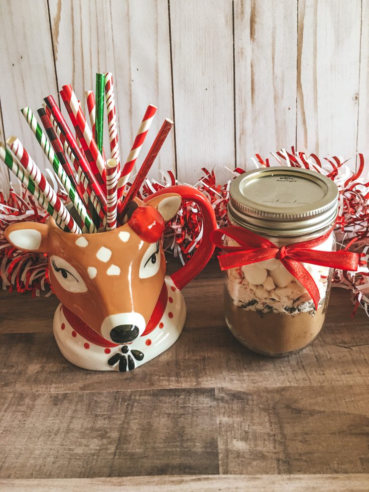 a mason jar filled with hot chocolate mix sitting next to reindeer mug filled with colorful paper straws