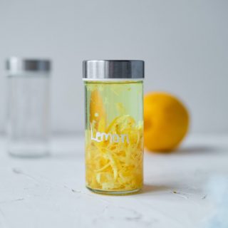 a glass bottle filled with lemon peels and vodka to make extract