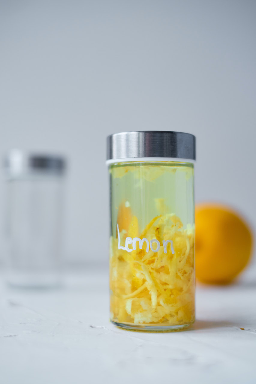 labeled glass jar filled with lemon peels and vodka to make Homemade Lemon Extract