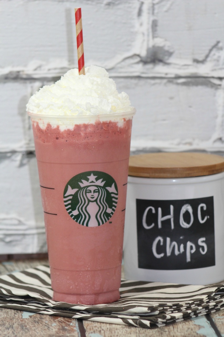 cotton candy Frappuccino sitting on a black and white striped napkin next to a container that says choc chips