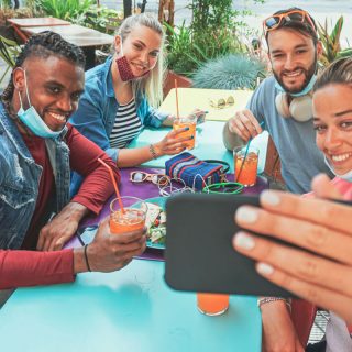 People sitting at a table taking a selfie with masks