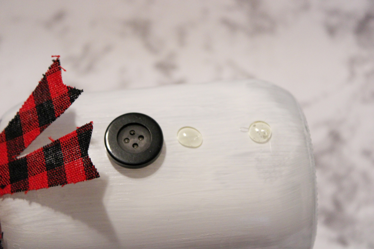 Gluing buttons on DIY mason jar snowman
