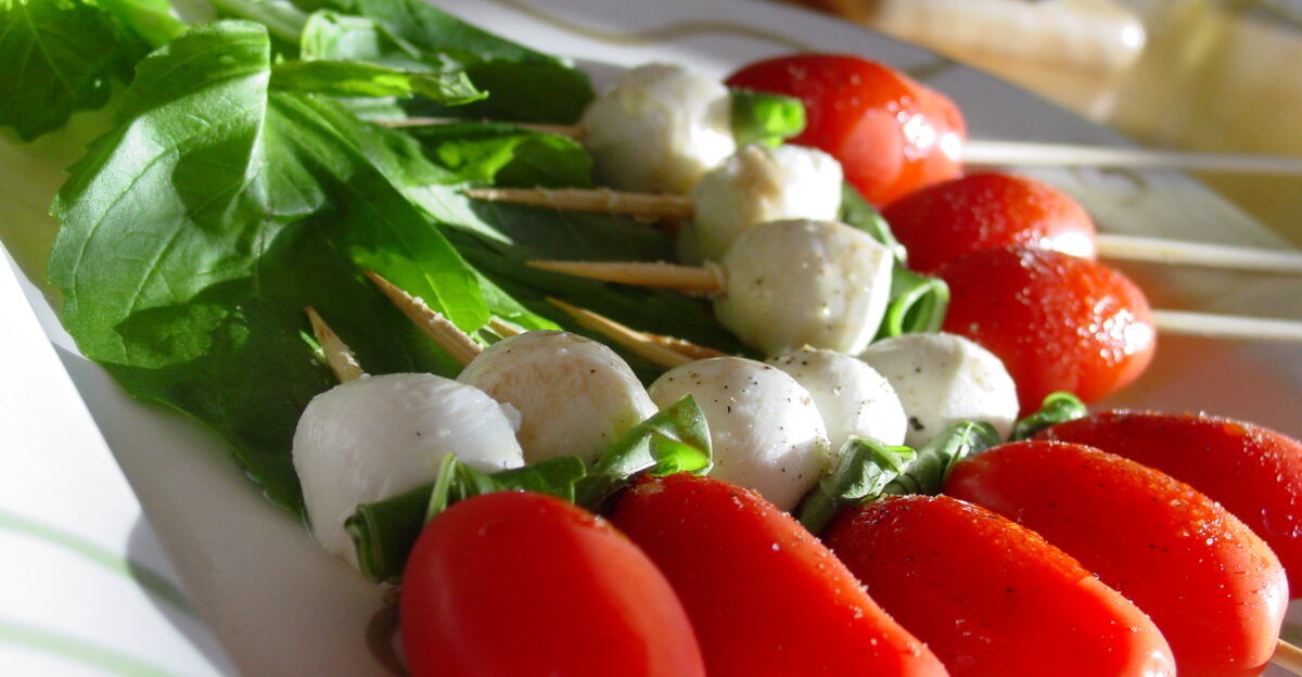 Caprese salad on a stick Grape tomato basil leaf bocconcini Drizzled with olive oil balsamic