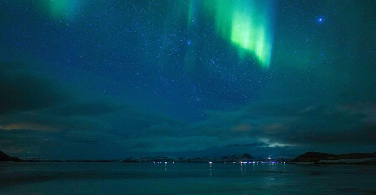 Northern lights in the night sky over M vatn Iceland Polar aurorae are caused by the collision of charged particles in the solar wind with gases in the upper atmosphere These collisions generate tiny flashes of light that fill the sky with veils of colour