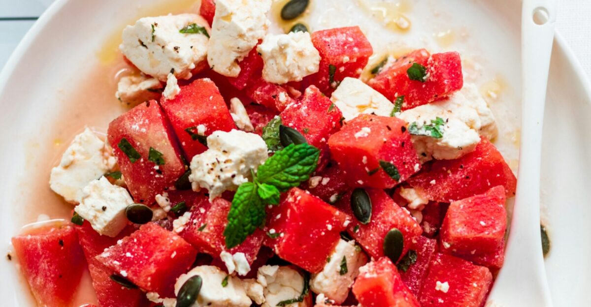 a plate of watermelon and feta salad next to a glass of water