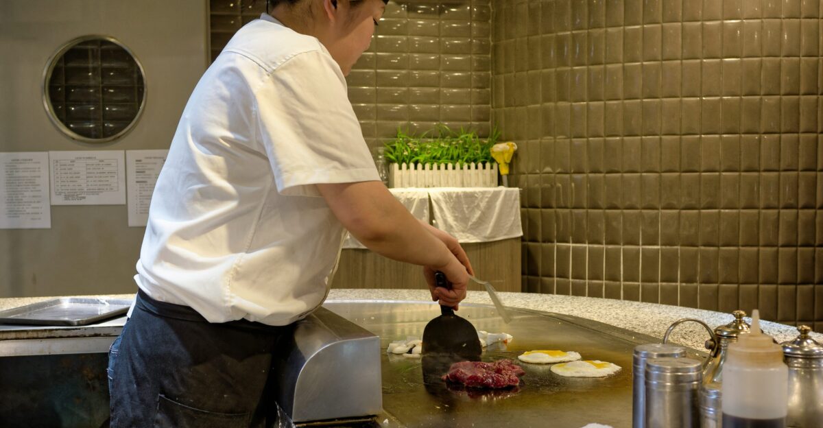 A man in a kitchen cooking food on a grill