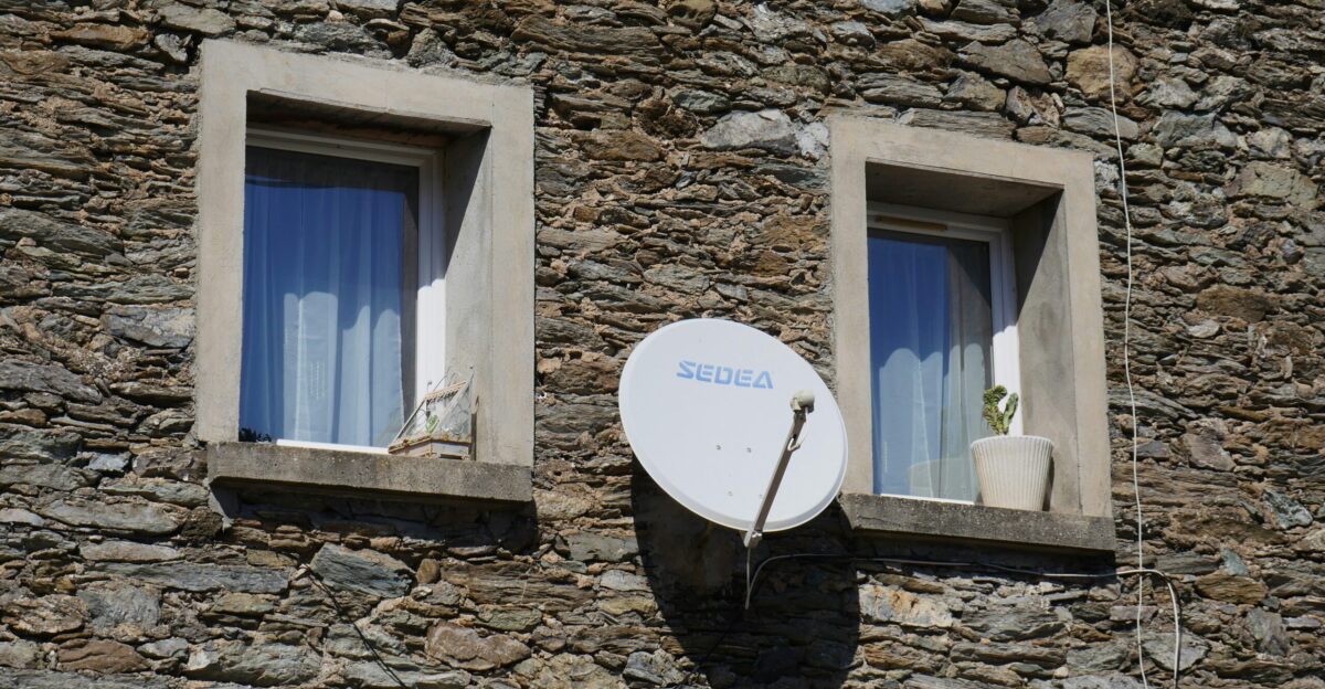 A satellite dish mounted to the side of a stone building