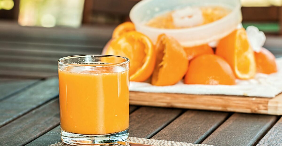 Glass of fresh orange juice with sliced oranges on wooden table perfect for breakfast and healthy living
