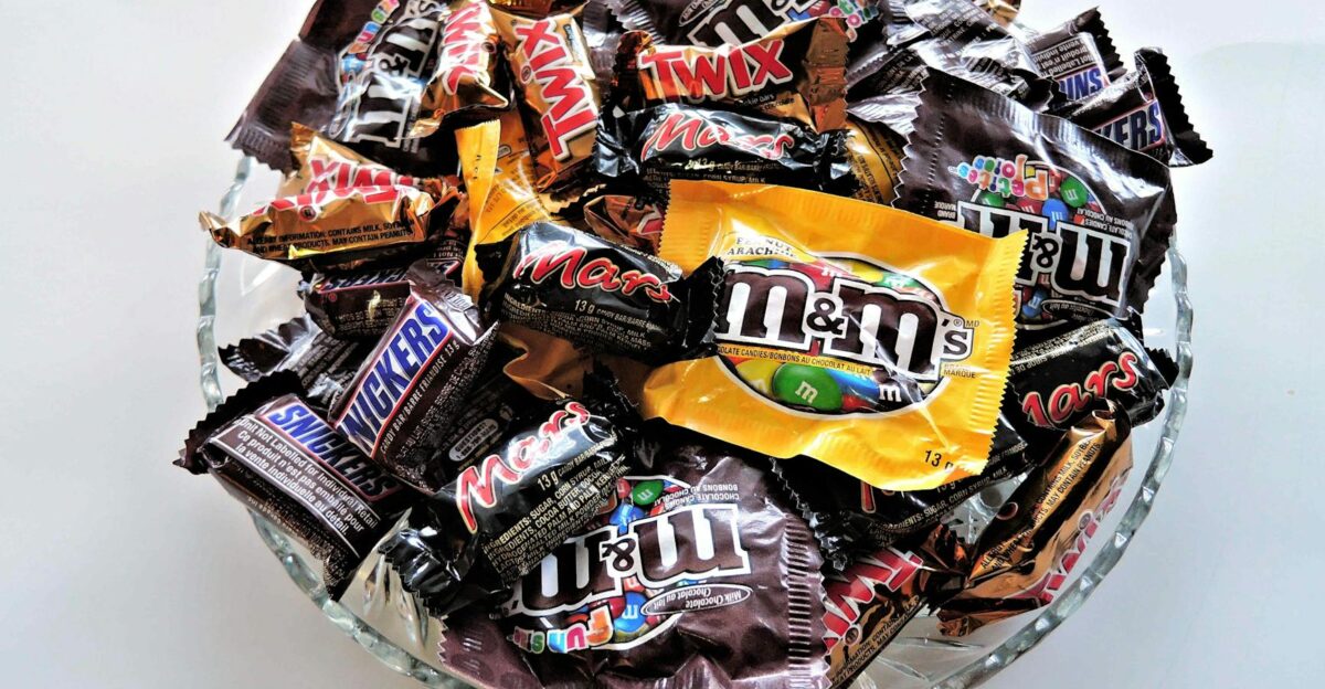 A bowl filled with various chocolate candies including Twix Snickers and M Ms creating a vibrant dessert spread