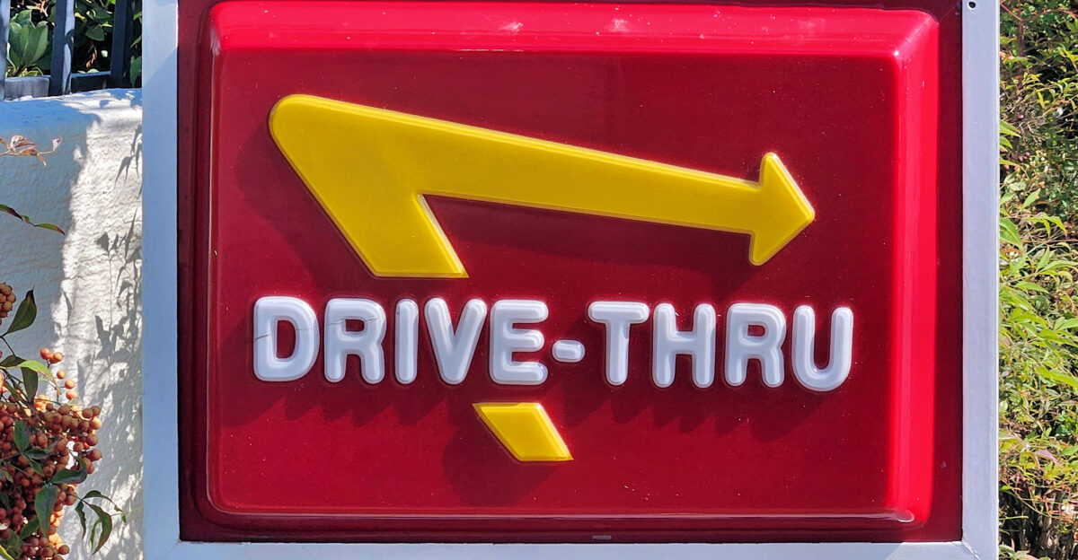 A stylized directional arrow pointing to the entrance of the drive-thru lanes of an In-N-Out Burger restaurant