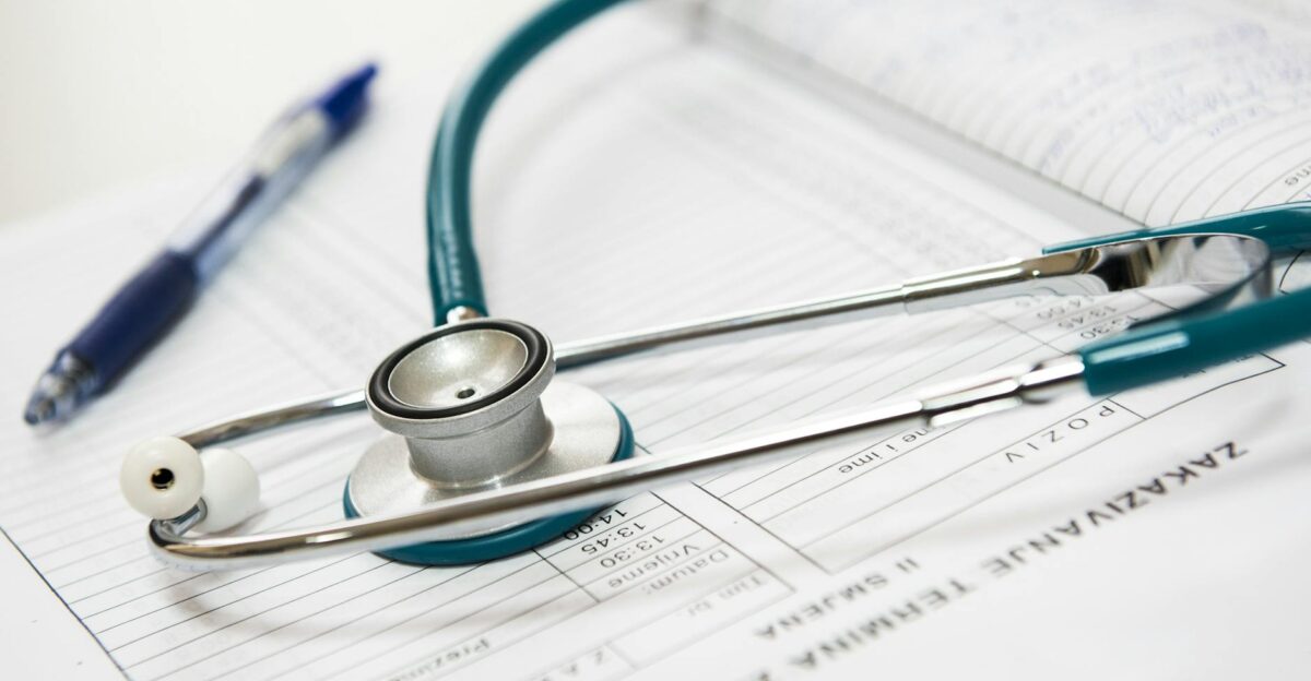 A stethoscope and pen resting on a medical report in a healthcare setting
