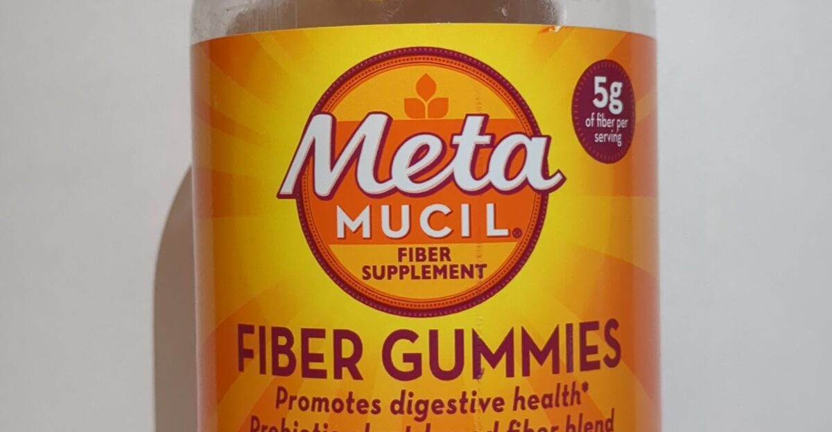 A plastic bottle on a white background with an orange label that says MetaMUCIL and under it FIBER GUMMIES with a brief description of what the supplement does Underneath there is a green banner that says NO SUGAR ADDED and underneath that 72 GUMMIES In the top right corner there is a purple circle that says 5g of fiber per serving