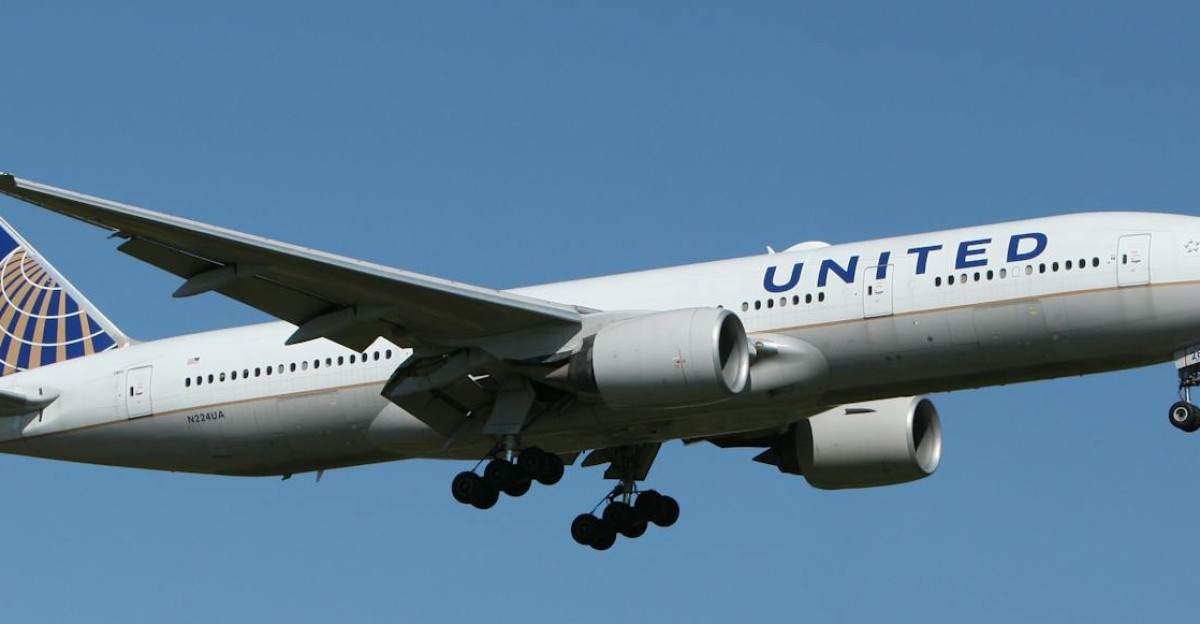 A United airliner flying against a clear blue sky showcasing air travel