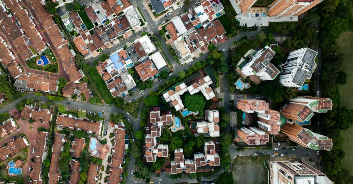 High-angle drone shot capturing an urban neighborhood with residential buildings and pools
