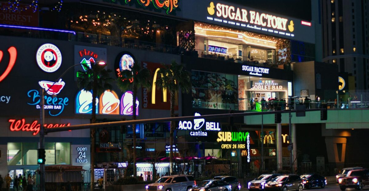 City nightlife scene with bustling streets and illuminated storefronts showcasing popular brands