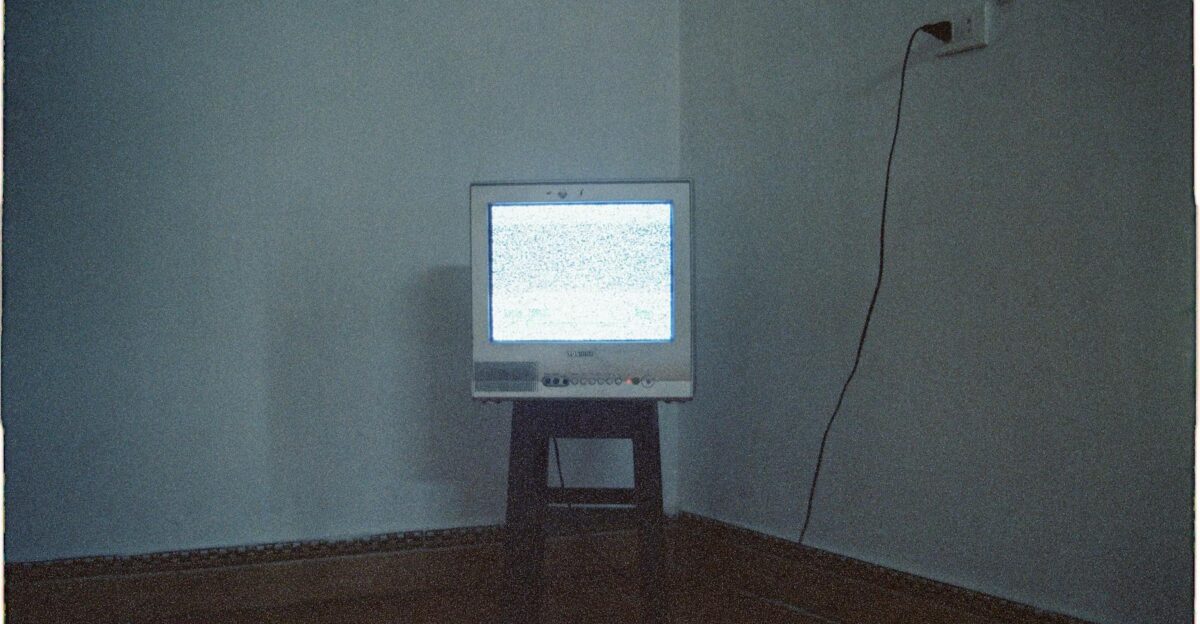 A vintage CRT television displaying static noise in a minimalist room setting
