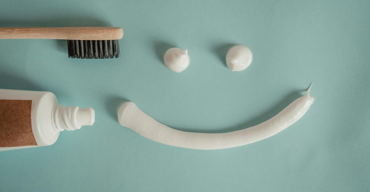 A playful arrangement of toothpaste and toothbrush forming a smile on a blue background