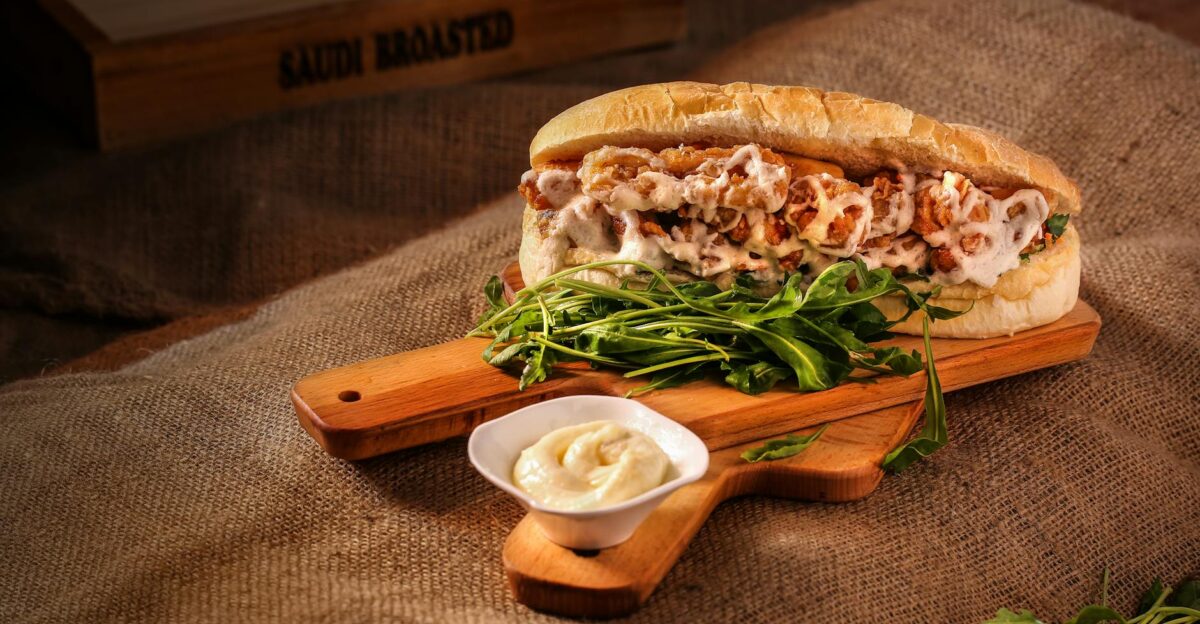 Mouth-watering chicken sandwich with greens on a rustic wooden board