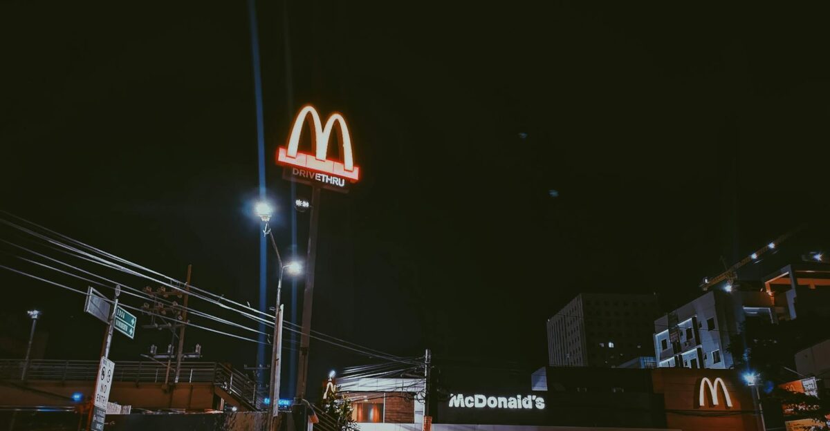 A brightly lit McDonald s restaurant in a city setting during nighttime showcasing neon signage