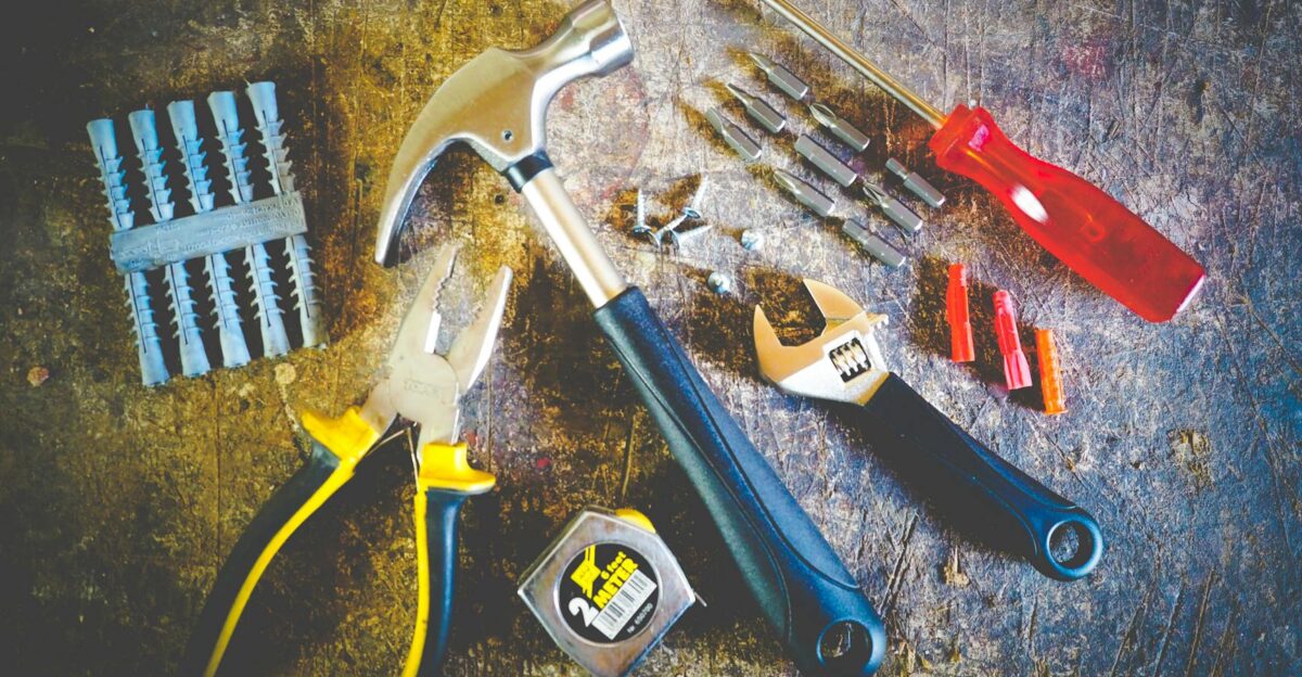 Collection of hand tools including hammer screwdriver and pliers in a workshop setting