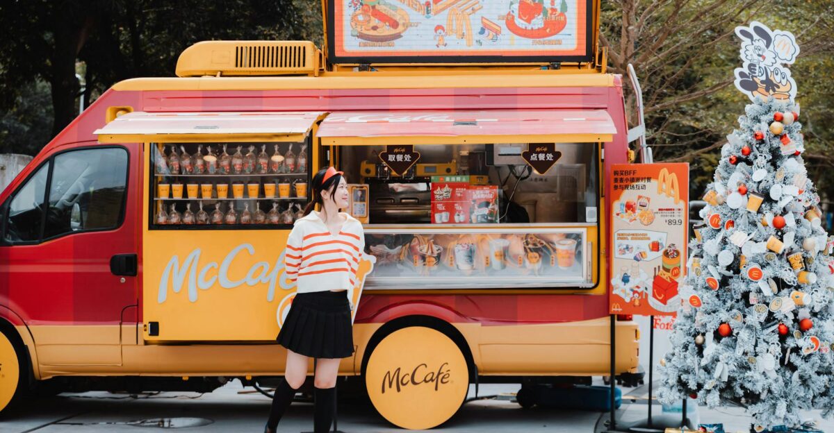A McDonald s food truck with festive holiday decor and a woman standing nearby