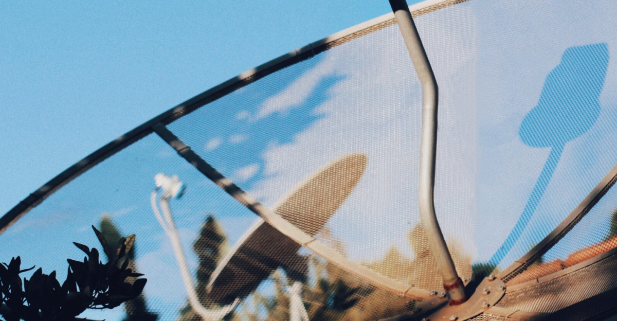Modern satellite dish pointing skyward against a vivid blue sky in Rio Vermelho, Brazil.