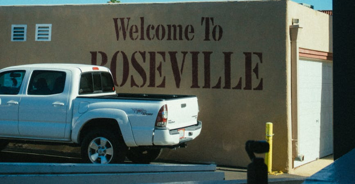 Street view of Roseville welcome sign with a pickup truck and palm tree under a blue sky