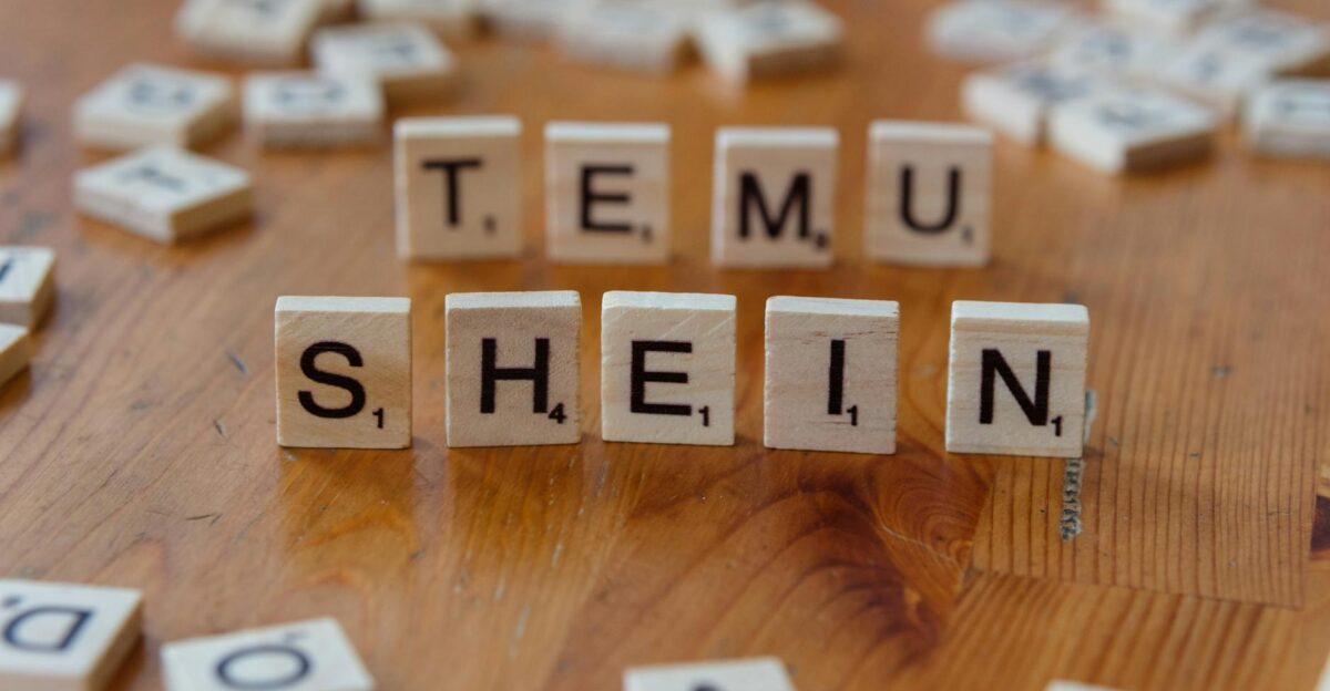 Scrabble tiles spelling TEMU SHEIN on a wooden table representing fashion brands