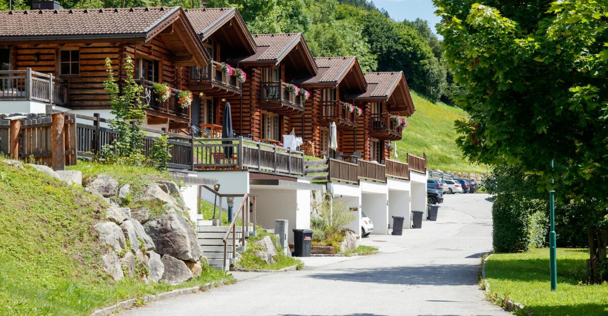 A row of picturesque log cabins surrounded by lush greenery on a sunny day