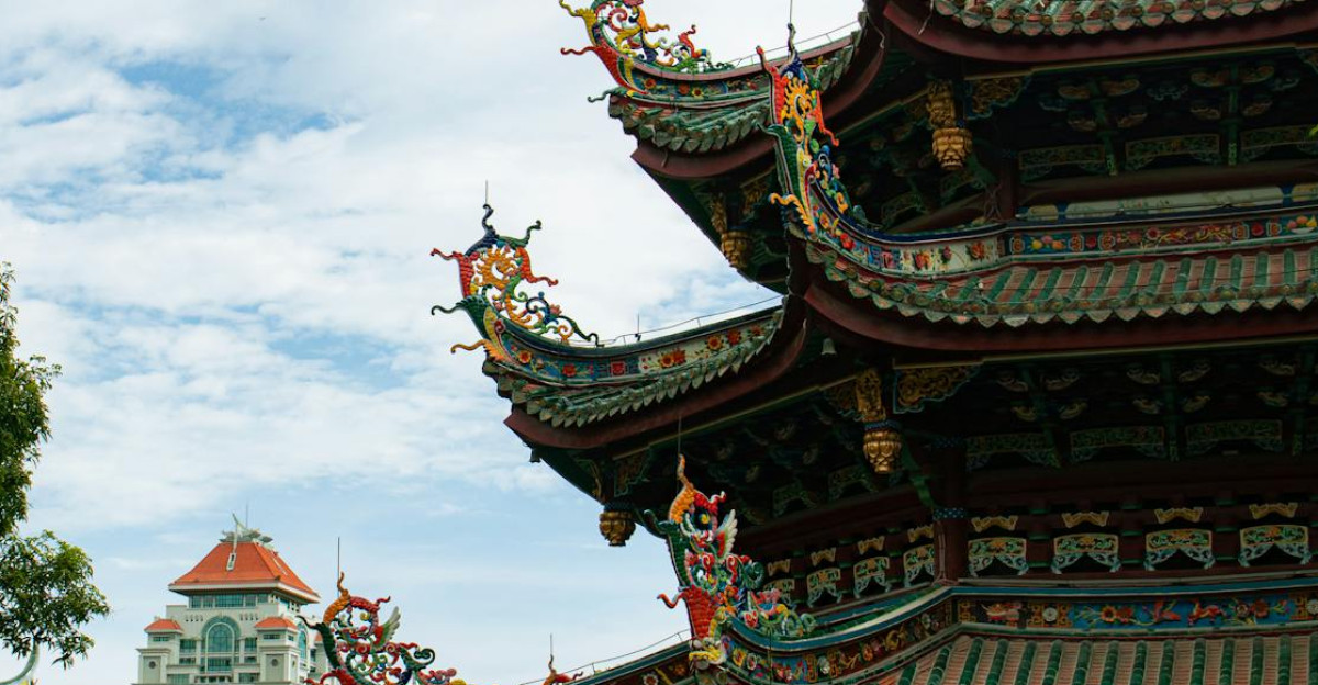 A scenic view of a traditional Asian temple with ornate roof details surrounded by lush greenery under a bright sky