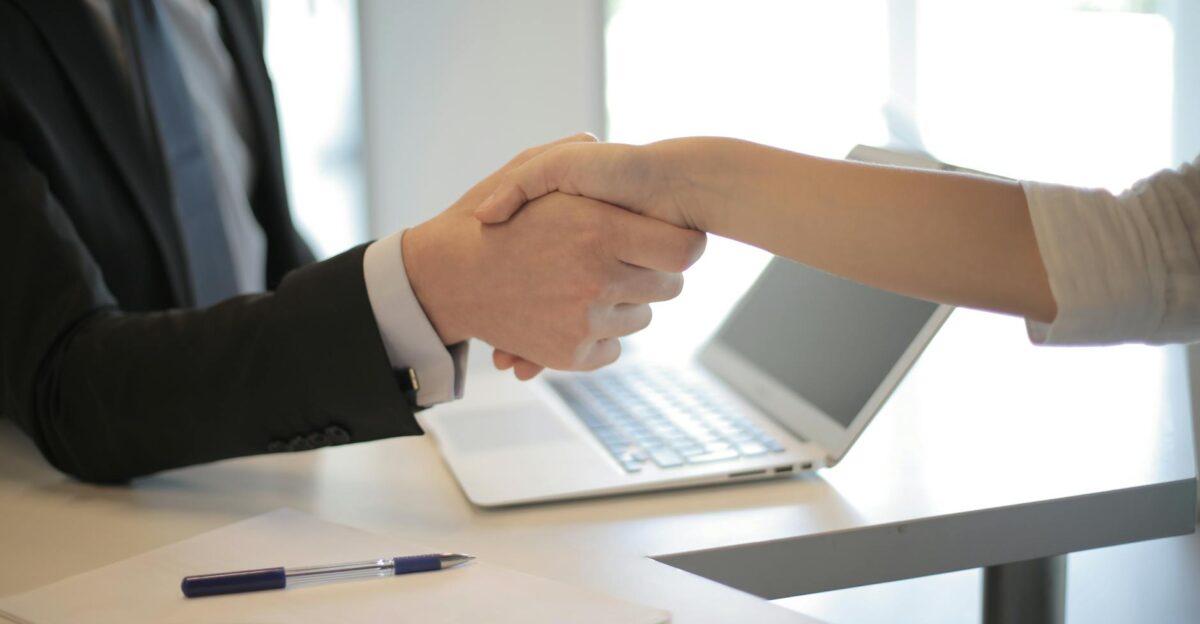 Close-up of a professional handshake over a laptop during a business meeting in an office