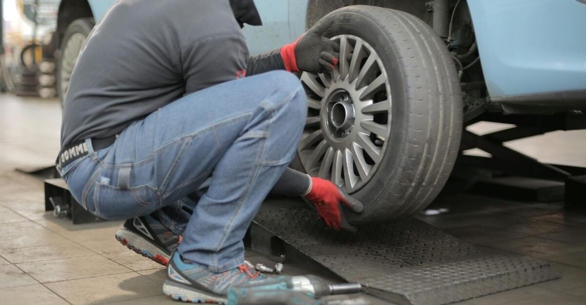 Mechanic changing a car tire indoors using tools for vehicle maintenance