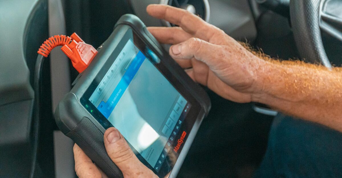A mechanic uses a diagnostic tablet inside a car for vehicle analysis