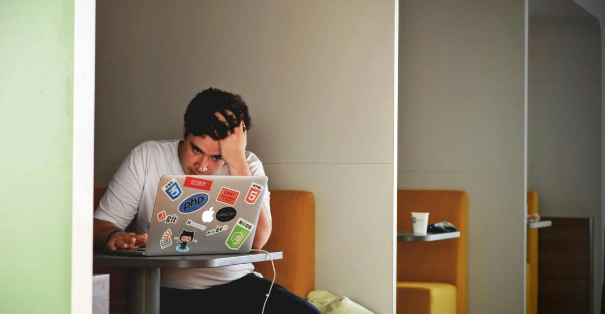 Man showing stress and frustration while working remotely on a laptop indoors