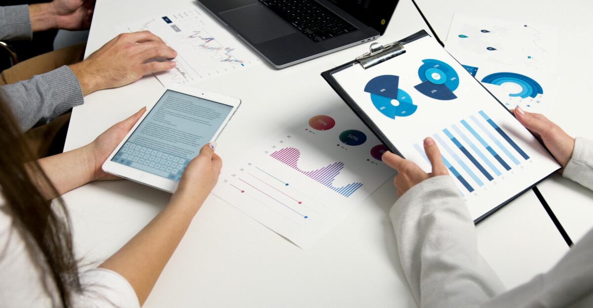 Team analyzing financial charts and digital reports during a business meeting
