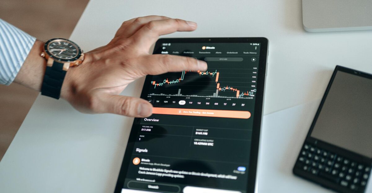 A person analyzing cryptocurrency market trends on a tablet device displaying digital charts