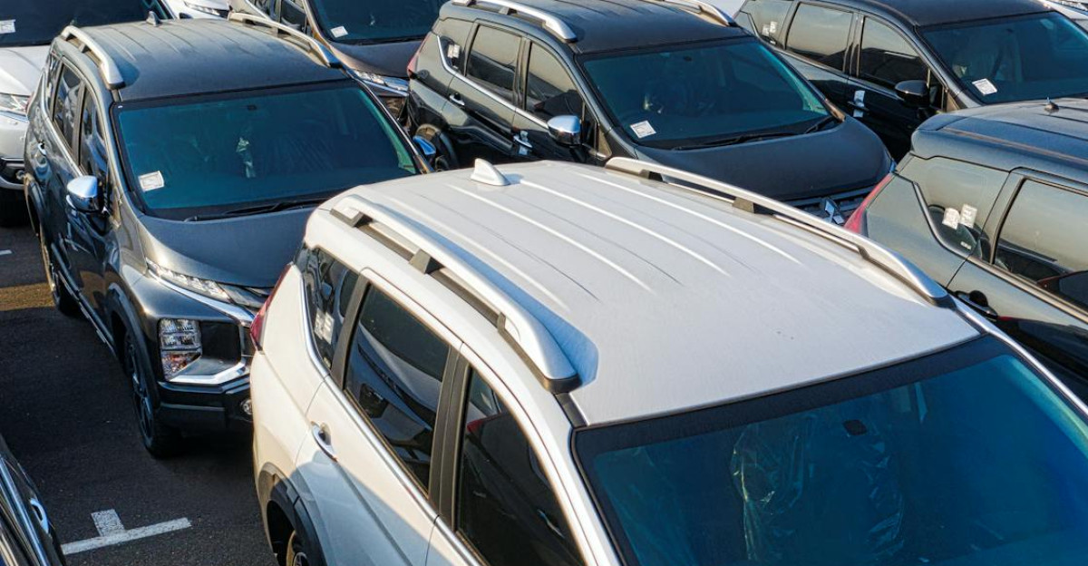 Modern sparkling clean new automobiles on asphalt parking near factory of manufacture in daytime