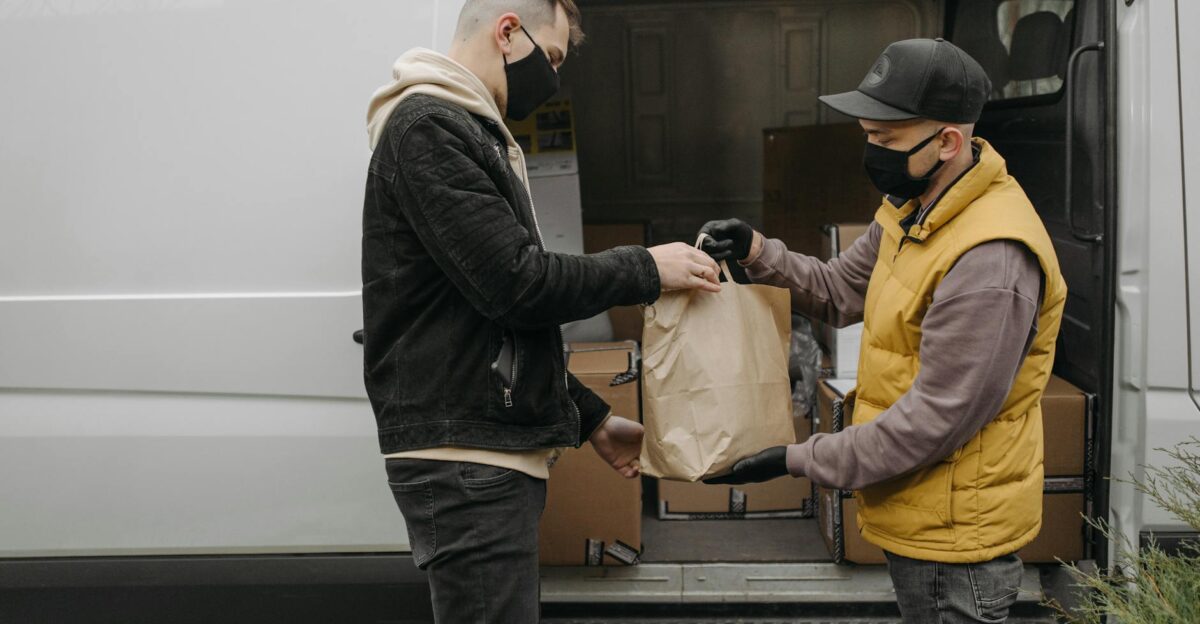 Masked deliveryman hands package to customer from van ensuring safety and hygiene
