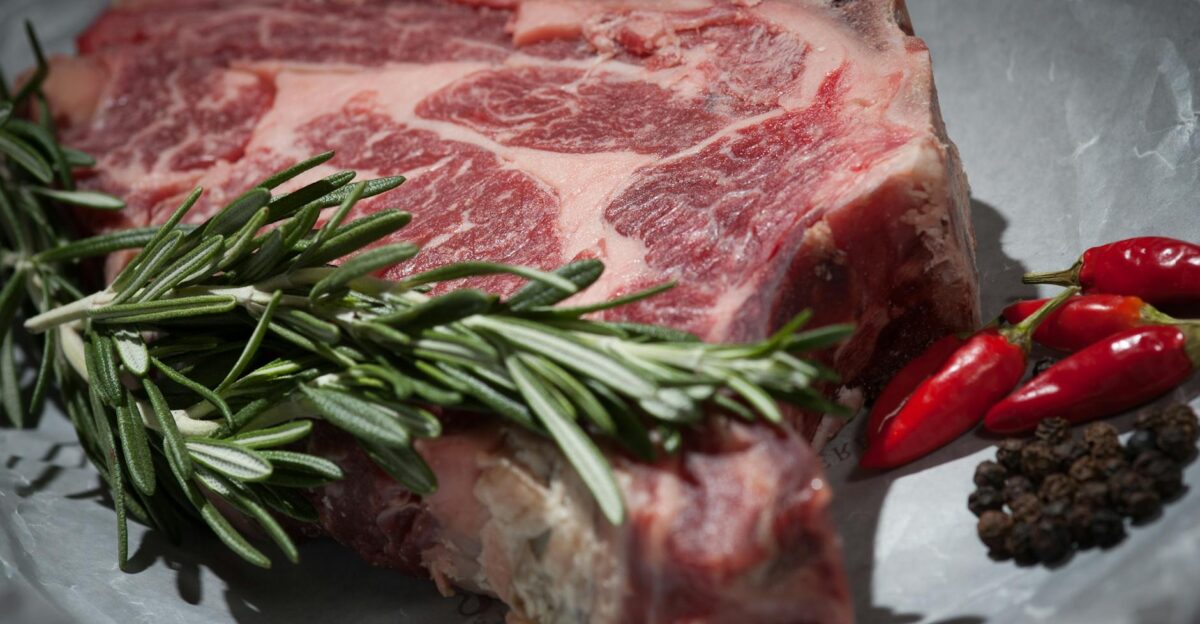 Close-up of a raw steak garnished with rosemary and chilies ideal for cooking concepts