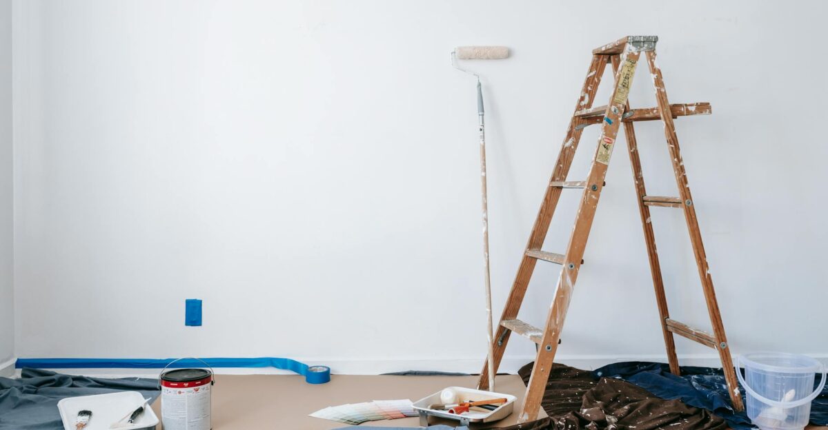 A room prepared for renovation with a ladder paint supplies and drop cloth