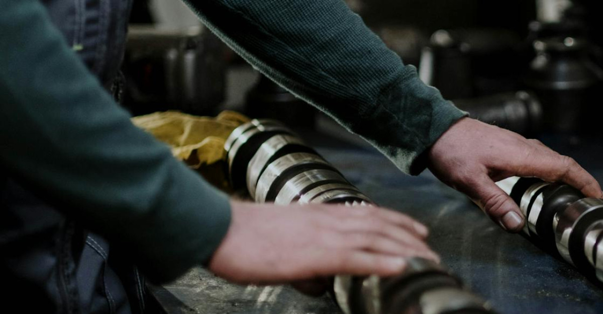 Worker handling camshafts and cylinder head in a mechanic workshop