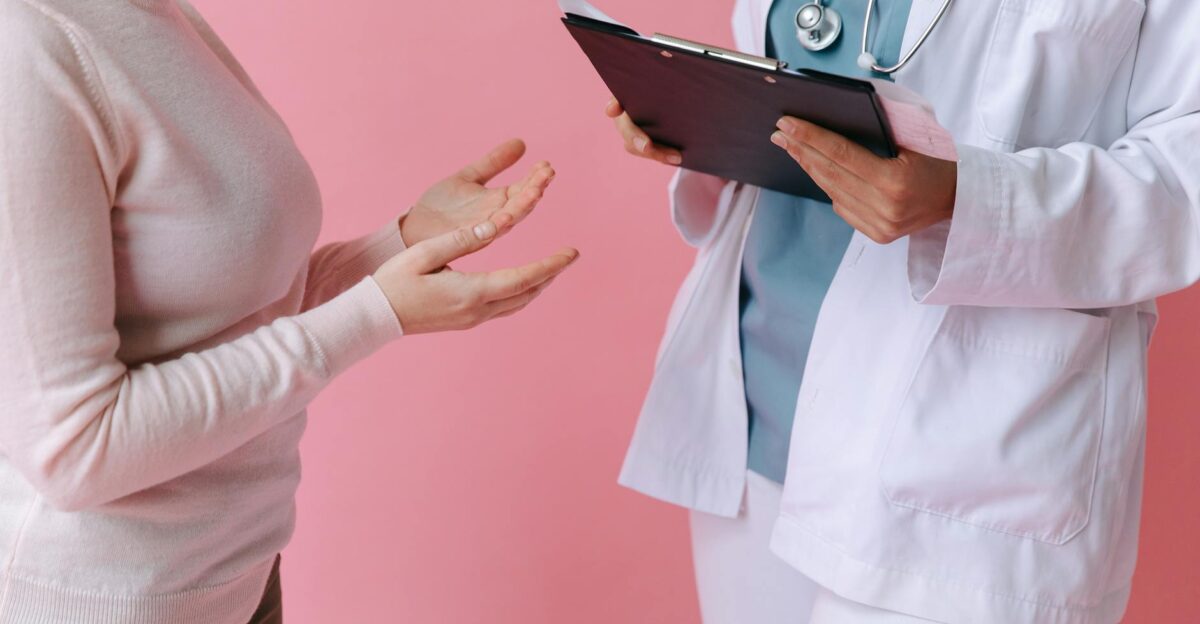 Close-up of a patient consulting a doctor with a clipboard in a medical setting